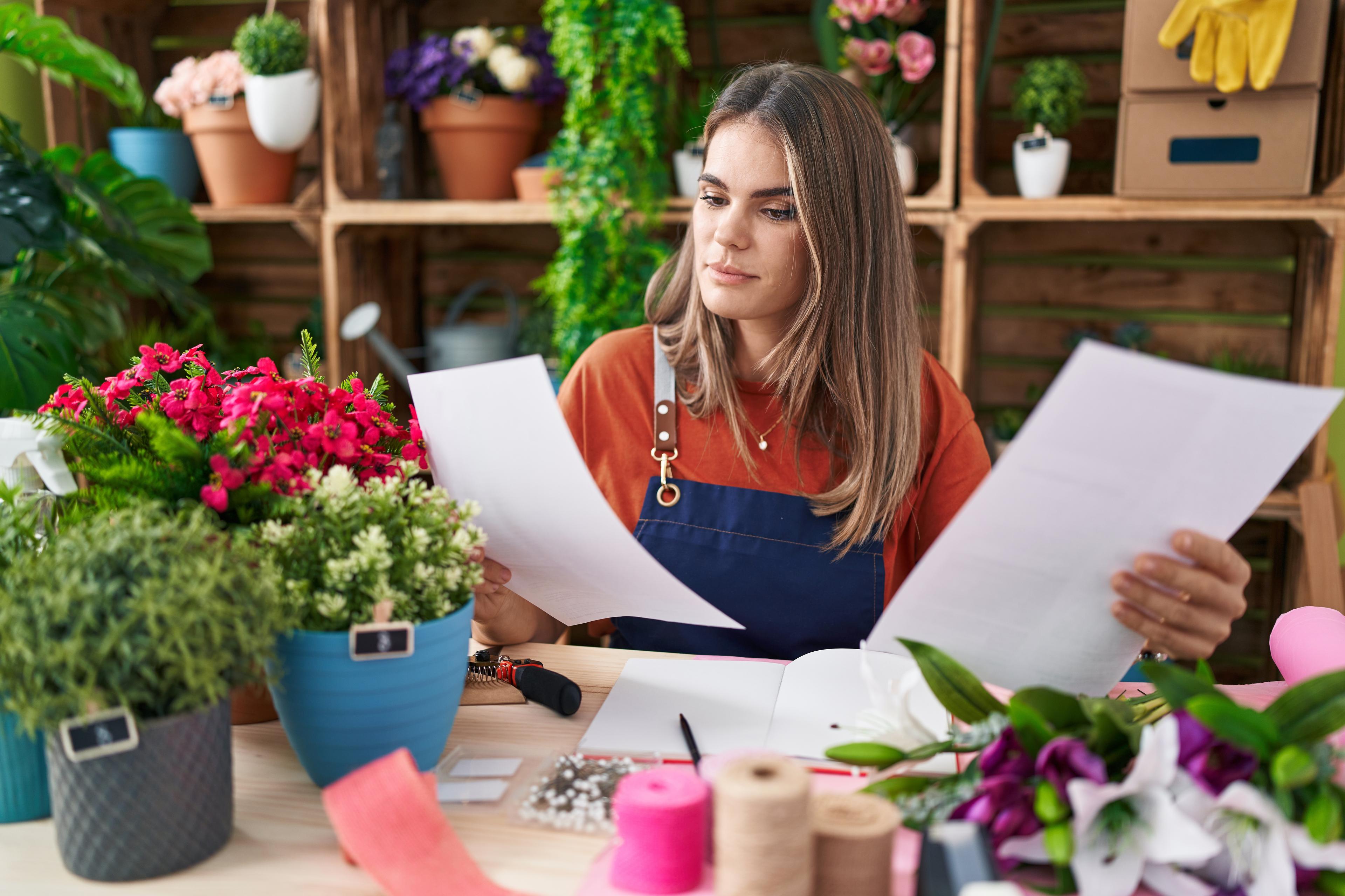 Photo d'une fleuriste lisant des documents sur une table de son atelier - Étude d'investissement